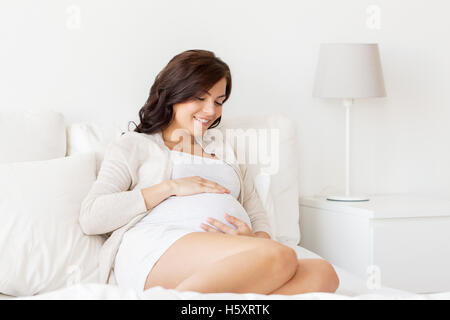 glücklich schwanger Frau auf Bett zu Hause Stockfoto