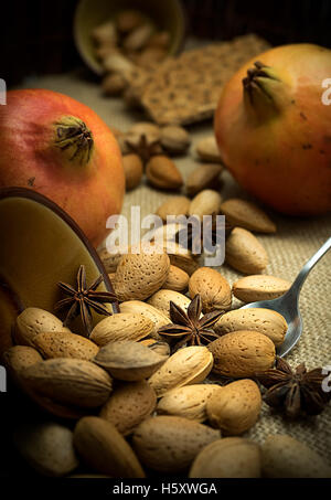 Herbst Zusammensetzung der Granatäpfel auf einem rustikalen dunklen Hintergrund mit Mandeln, Marillenmarmelade und Sternanis Stockfoto