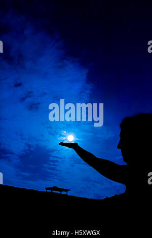 Frau mit vollen Mond in der hand gegen Nachthimmel Stockfoto