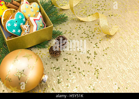 Weihnachts-Geschenk-Box mit Lebkuchen und Dekoration auf festliche Goldgrund Stockfoto