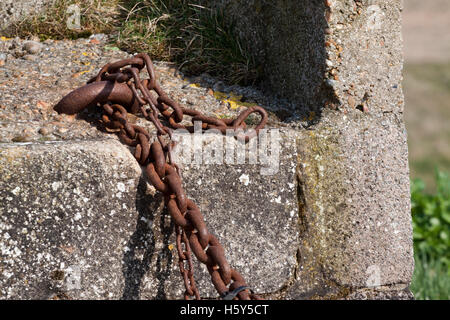 Rostige Kette zu einem Ring befestigt, die in Beton gesetzt Stockfoto