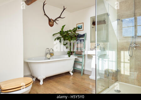 Ein modernisiertes Badezimmer in einem viktorianischen Haus, mit Holzboden, eine freistehende Badewanne & begehbarer Dusche Stockfoto