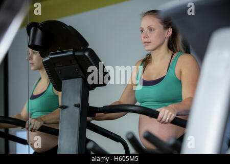 Schwangere Frau Training auf Crosstrainer Stockfoto