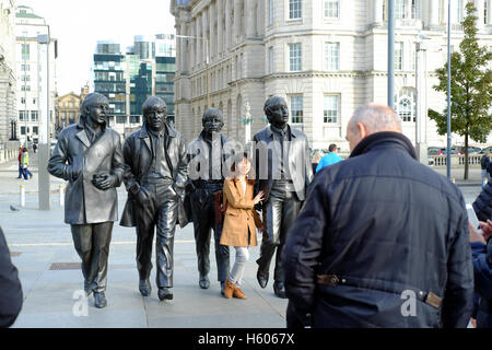 Ein japanischer Tourist stellt mit der Bronzestatue von The Beatles in Liverpool, England Stockfoto