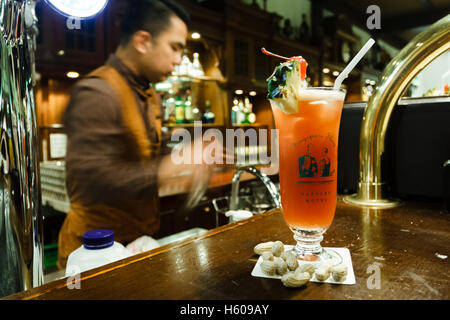 Ein Barkeeper mixt einen Singapore Sling in der Long Bar, Raffles Hotel, Singapur Stockfoto