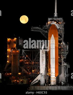 Ein Vollmond setzt in den Nachthimmel wie NASA Space Shuttle Discovery oben auf Kennedy Space Center Launch Pad 39A in Vorbereitung STS-110 Mission zur internationalen Raumstation ISS 11. März 2009 in Cape Canaveral, Florida sitzt. Stockfoto