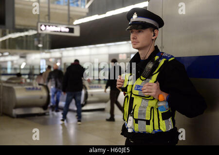 Ein Polizist steht in der Eingangshalle zur Canary Wharf u-Bahnstation. Stockfoto