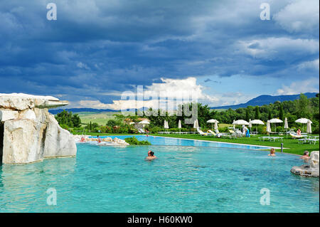 Der größte thermische Außenpool des Hotel Adler in Bagno Vignoni, unter einem dramatischen regnerischen Himmel. Stockfoto