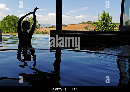 Die Silhouette einer Frau in den thermal-Innenpool von Fonteverde Natural Spa Resort in San Casciano dei Bagni, in der Nähe von Siena. Stockfoto