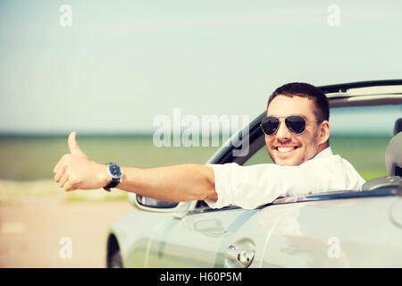 glücklicher Mann Auto fahren und zeigt Daumen hoch Stockfoto