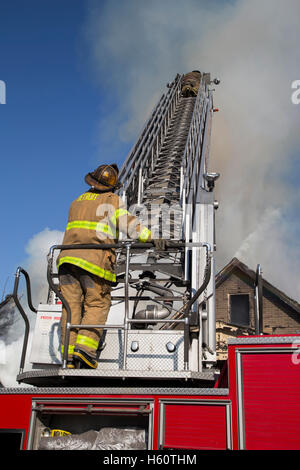 Feuerwehrmann, der die Leiter am Ort des Hausbrands betreibt, Detroit, Michigan, USA, von David Traiforos/Dembinsky Photo Assoc Stockfoto