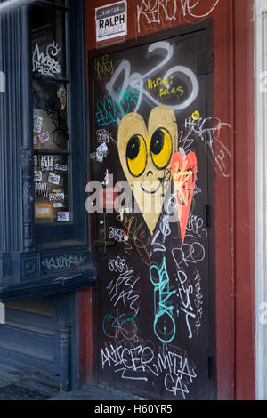 Eine Tür auf East Houston Street in lower Manhattan mit Graffiti, street Art und Aufkleber. Stockfoto