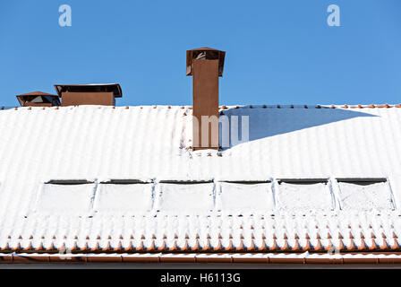 Kamin und Gaube Fenster im Dach mit Schnee bedeckt Stockfoto