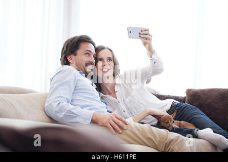 Glückliches Paar unter einem Selfie zusammen auf der Couch zu Hause Stockfoto
