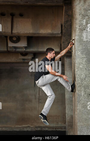 Männer T-shirt von Parkour im urbanen Raum. Er klettert die Wand. Sport in der Stadt. Bewegung ist Leben. Stockfoto