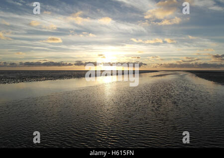 Gelb-weiße Sonnenuntergang unter grauen Stratocumulus Wolken über einem Ebbe Sand-Strand mit Meer-Wasser-Kanal, Fairhaven, Lytham Stockfoto