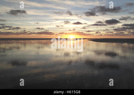 Graue Stratocumulus Wolken reflektiert in Meer Kanal Kreuzung Sandstrand Wasserfläche in Richtung gelb Sonnenuntergang, Fairhaven, Lytham Stockfoto