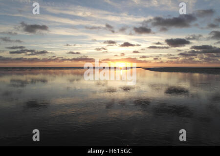 Graue Stratocumulus Wolken reflektiert in Meer Kanal Kreuzung Sandstrand Wasserfläche in Richtung gelb Sonnenuntergang, Fairhaven, Lytham Stockfoto