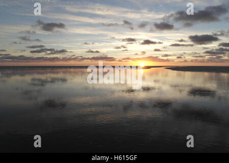 Gelbe Sonnenuntergang unter grauen Stratocumulus Wolken reflektiert in Meer Kanal Kreuzung Strandsand Wasserfläche, Fairhavem, Lytham, UK Stockfoto