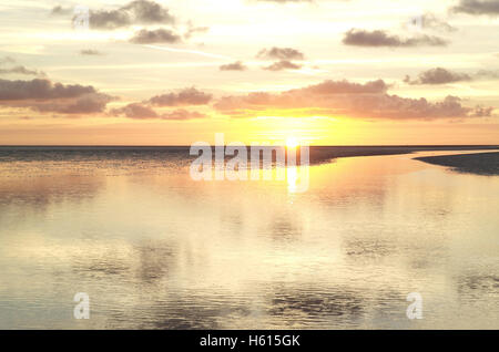 Blick über die Weite des Strandes, die gelbe Sonne Einstellung unter grauen Stratocumulus Wolken, Fairhaven, Lytham Sand mit Wasserkanal Stockfoto