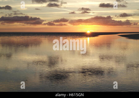 Gelbe Sonneneinstellung unter grauen Stratocumulus Wolken reflektieren Meer Wasser Kanal Kreuzung Ebbe Strand, Fairhaven, Lytham, UK Stockfoto