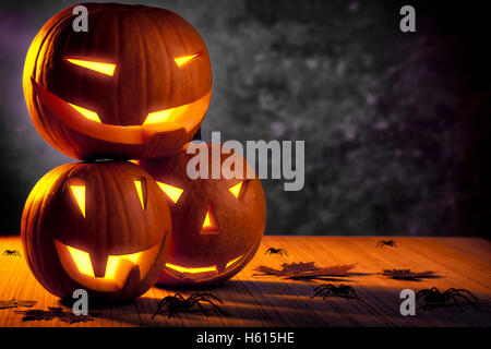 Halloween Kürbis Stilleben, drei Kürbisse mit glühenden gruselige Gesichter auf dem Tisch mit vielen widerlich Spinnen geschnitzt Stockfoto