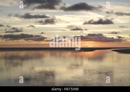 Graue Stratocumulus Wolken reflektiert im Meer Kanal Kreuzung Sandstrand Wasserfläche, zu orange sunset Glow Fairhaven, Lytham Stockfoto