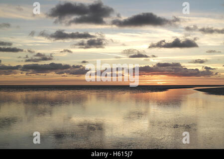 Viele dunkle graue Stratocumulus Wolken reflektiert in Sand Strand Meer-Wasser-Kanal in Richtung orange sunset Glow, Fairhaven, Lytham, UK Stockfoto