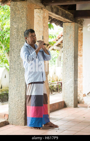 Mann bläst einen traditionellen Horn am Puja, Lankatilake Tempel aus dem 14. Jahrhundert, Kandy, Sri Lanka Stockfoto