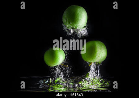 Drei grüne Äpfel Spritzer ins Wasser auf schwarzem Hintergrund. Stockfoto