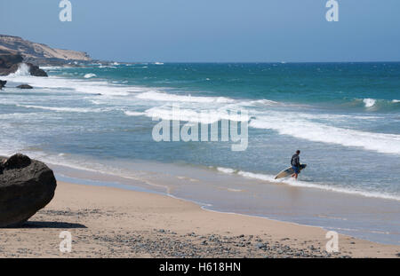 Fuerteventura, Kanarische Inseln, Nordafrika, Spanien: Wellen und ein Surfer, ein Surfbrett an der Playa de Garcey, einem schwarzen Strand an der Westküste Stockfoto