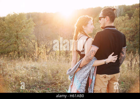 Mann und schwangere Frau umarmt Händchen haltend auf dem Hintergrund der wilden Natur, Herbst. Liebesgeschichte Stockfoto
