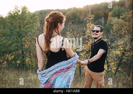 Mann und schwangere Frau umarmt Händchen haltend auf dem Hintergrund der wilden Natur, Herbst. Liebesgeschichte Stockfoto