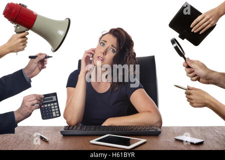Business-Frau sitzt am Schreibtisch umgeben von vielen Händen halten von Gegenständen Stockfoto