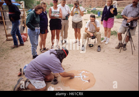 Navajo Führer schaffen eine Sandmalerei vor Gruppe von Wanderern, Canyon de Chelly National Monument, Arizona Stockfoto