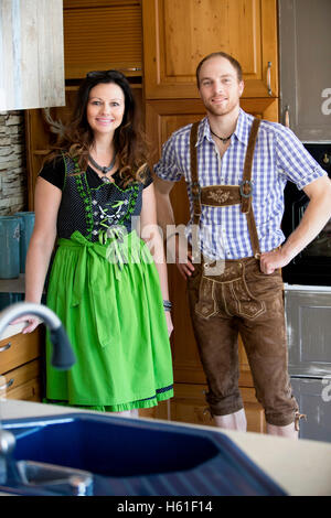 paar in bayerischer Tracht stehen in Küche und Blick in die Kamera Stockfoto