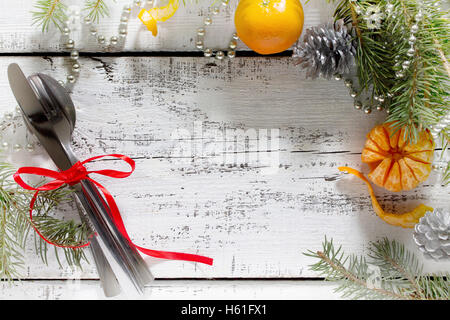 Weihnachtsbaum Zweig, Schmuck und Besteck auf einem weißen Holztisch. Stockfoto