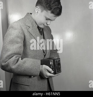 Anfang der 1950er Jahre, historisch, Schule junge stehend nehmen ein Foto in Hüfthöhe mit einem britischen 6-20 'Brownie' E Doppellinsen reflex-Box-Film-Kamera mit zwei Sucher gemacht. Stockfoto