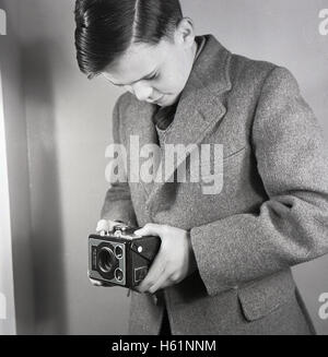 Anfang der 1950er Jahre, historisch, Schule junge stehend nehmen ein Foto in Hüfthöhe mit einem britischen 6-20 'Brownie' E Doppellinsen reflex-Box-Film-Kamera mit zwei Sucher gemacht. Stockfoto