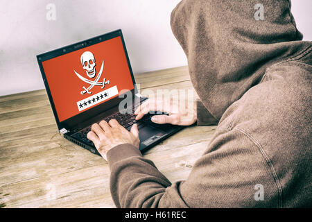 Rückansicht eines Hackers tragen einen Hoodie und ein Kennwort auf einem Laptop-Bildschirm zu stehlen Stockfoto