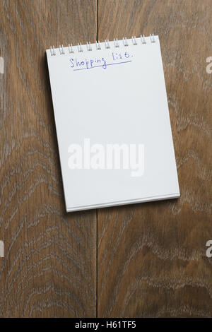 Einkaufsliste auf Notizblock auf Holztisch Stockfoto