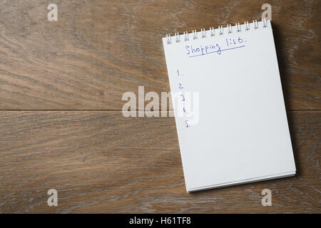 Einkaufsliste auf Notizblock auf Holztisch Stockfoto