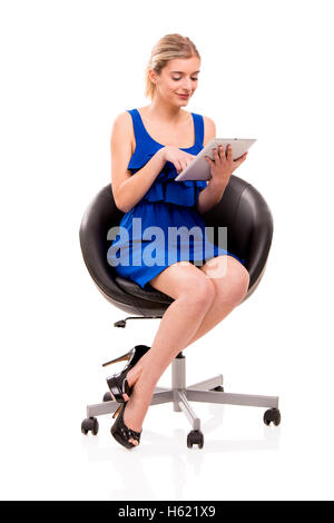 Schöne Frau sitzend auf einem Stuhl mit einem Tablet, isoliert auf weißem Hintergrund Stockfoto