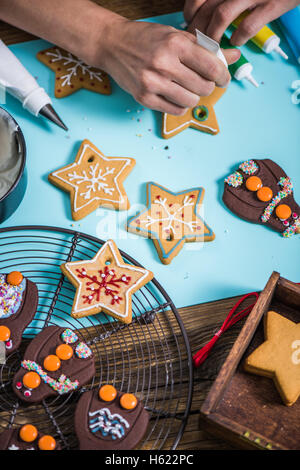 Draufsicht auf Tisch mit Lebkuchen Weihnachtsplätzchen verziert durch Frau Hände Stockfoto