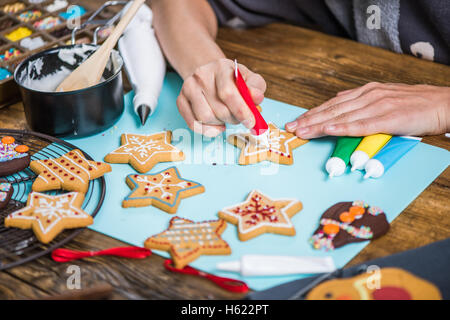 Frau Lebkuchen Weihnachtsplätzchen mit Puderzucker dekorieren Stockfoto