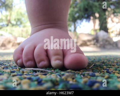 11 Monate altes Baby Boy Fuß über Playpark Gummiboden Stockfoto