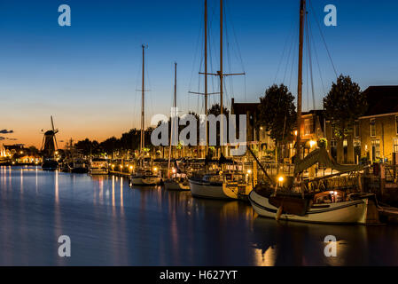 Zierikzee, Niederlande - 5. Oktober 2016: Boote und Windmühle in der Nacht im Nieuwe Haven in Zierikzee in Zeeland. Stockfoto