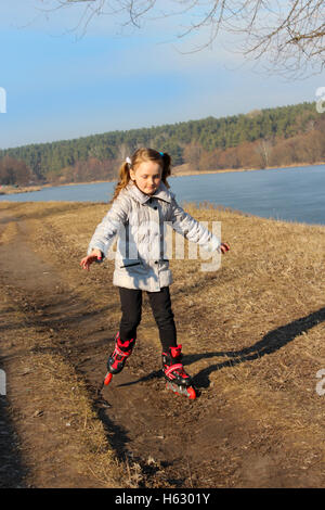 junges schönes Mädchen geht in Inline Skates auf dem Boden Stockfoto