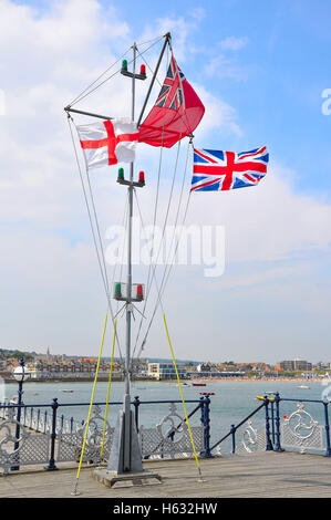 St Geoge Cross, der Handelsmarine Fähnrich und Union Jack-Flaggen auf Swanage Pier, Dorset. Stockfoto