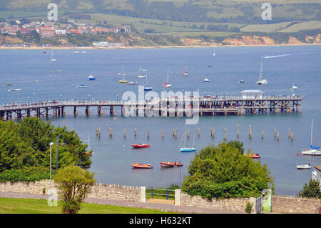 Boote liegen in der Swanage Bay neben dem neuen und den Überresten des alten Piers in Dorset England. Stockfoto